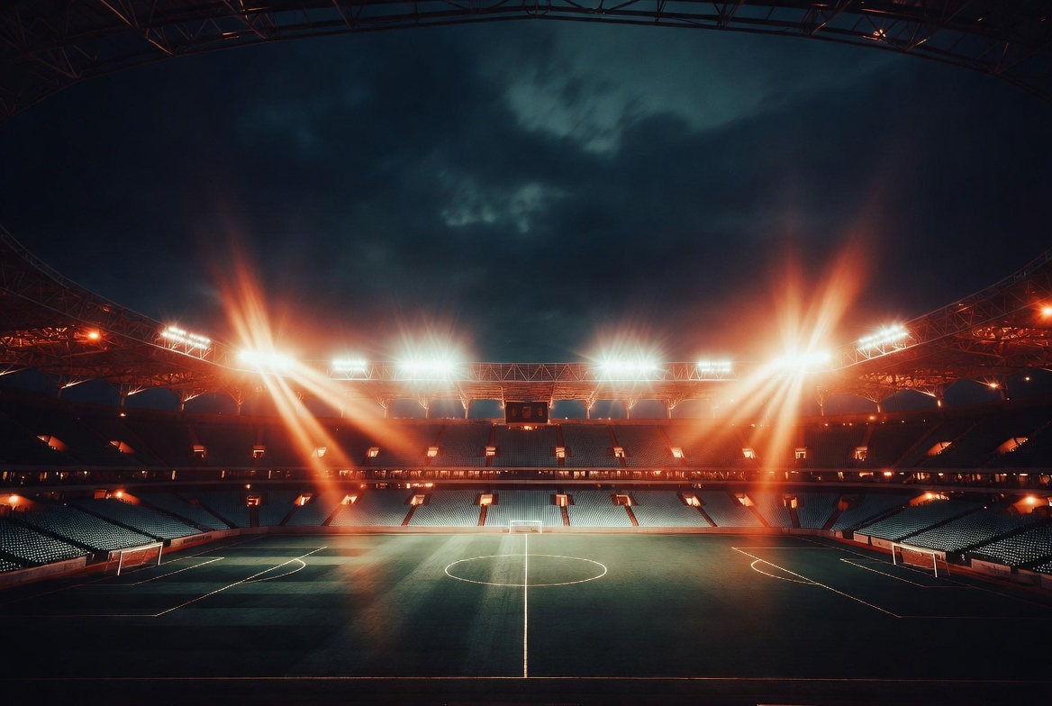 Dramatic night stadium with orange floodlights illuminating the empty pitch