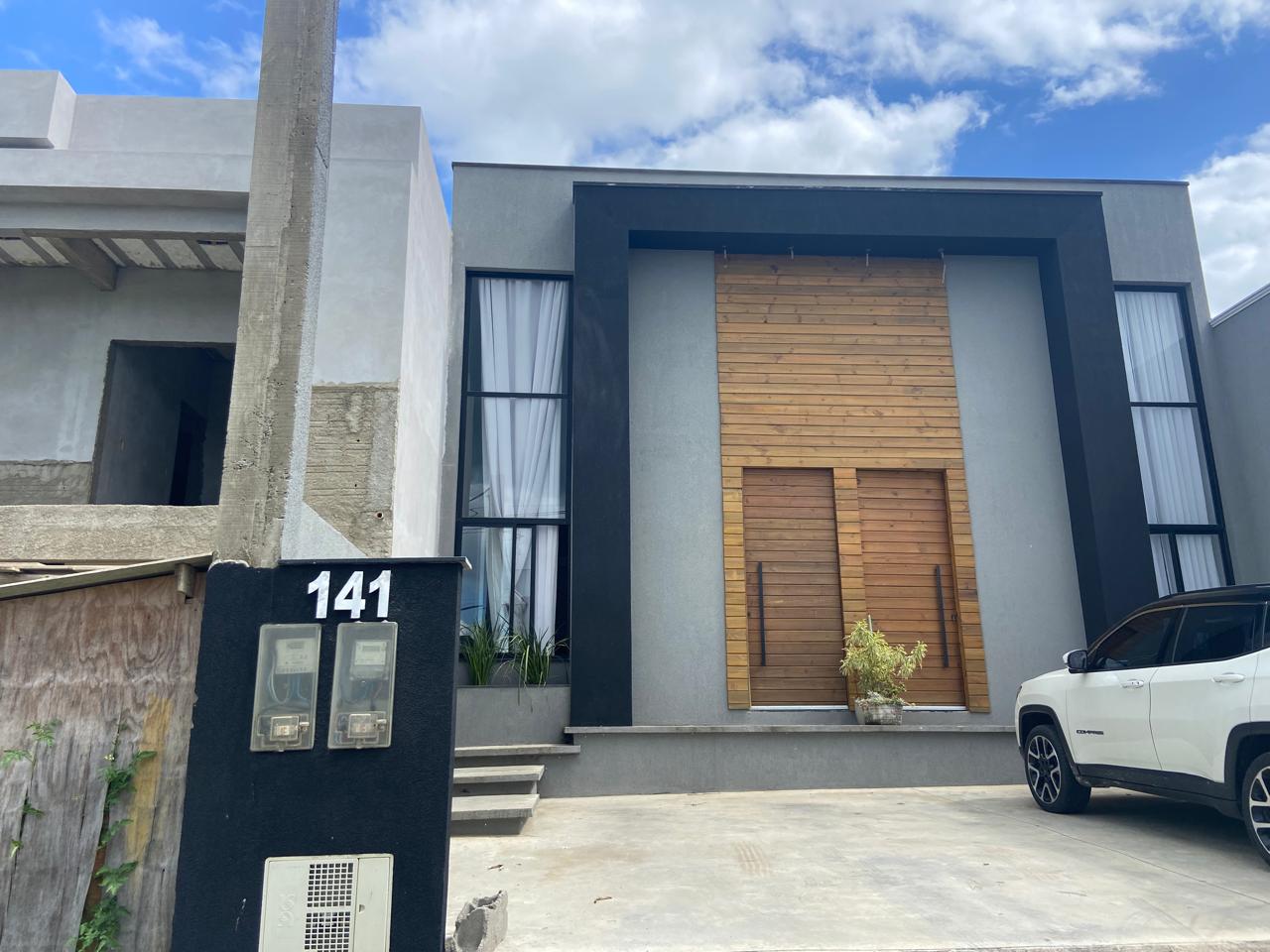 Fachada moderna com revestimento de madeira e porta pivotante construída pela My Home